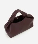 Cartera mediana de diseño estructurado en color bordó, confeccionada en poliuretano con acabado liso. Presenta asas de mano integradas con detalle fruncido, correa larga ajustable y desmontable, y cierre superior con cremallera.