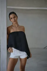 Top strapless negro de corte asimétrico, con diseño holgado y acabado satinado.