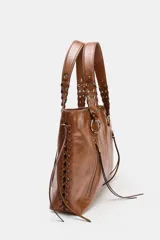 Bolso shopper de hombro color negro, con detalle de flecos y trenzados en el cuerpo. Tiene doble cremallera metálica, asa doble con detalles metálicos y trenzados, y un bolsillo interior. El cierre es mediante cremallera metálica.