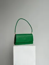 Cartera verde con textura símil piel de serpiente, para usar al hombro, con doble compartimiento interno, dije de marca metálico y cerramiento con broche imán.