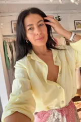 Camisa de algodón color amarillo pastel, con cuello clásico, cierre frontal de botones y mangas largas con puños.