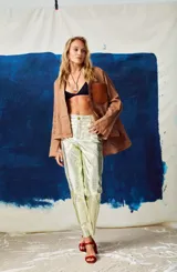 Pantalón de cuero tiro alto y corte recto, color turquesa metalizado, con cierre frontal y botón, bolsillos funcionales.