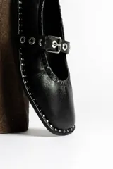 Ballerinas negras de cuero con correa sobre el empeine, hebilla metálica y tachas plateadas.