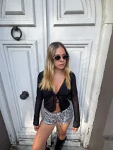 Top negro traslúcido de mangas largas con escote en V y lazo en el centro.