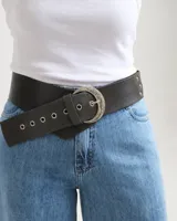 Faja ancha de cuero negro con hebilla metálica plateada y detalles de ojalillos en el extremo.