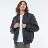 Campera estilo aviador negra, con cierre frontal, cuello redondo y puños y cintura elásticos. Presenta bolsillos de fuelle con doble entrada en la parte inferior y un bolsillo con cierre en la manga izquierda.