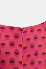 Vestido corto de cuello redondo y manga corta fluida, con cierre de cremallera oculta en la espalda. Presenta un estampado geométrico de círculos en tonos rosados y marrones.