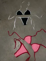 Conjunto de bikini negro con ribete blanco, compuesto por un corpiño triangular con tirantes finos y una bombacha tipo short con volados.