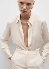 Camisa de corte recto y tejido satinado con acabado fluido. Presenta cuello clásico, cierre frontal de botones y mangas largas con puños abotonados.