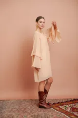 Vestido corto color salmón claro, de mangas largas con volados y corte suelto.