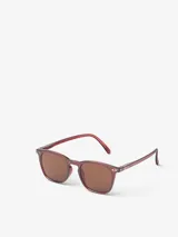 Lentes de sol Izipizi Sun E Red Tape, con montura trapezoidal color rojo y lentes marrones.