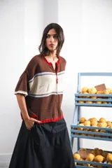 Remera de punto con diseño retro de bloques de color en marrón, crema y celeste. Presenta cierre frontal, cuello redondo, mangas cortas y tejido calado en la parte inferior. Incluye detalle de logo en relieve en el frente.