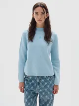 Polera de punto en color celeste, con cuello alto y manga larga. Presenta un pequeño logo bordado en el centro del pecho y terminaciones en tejido acanalado.