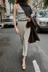 Pantalón de tiro alto y corte tobillero, confeccionado en tejido de aspecto denim oscuro. Presenta diseño de pinzas frontales, bolsillos laterales y cierre frontal con cremallera, botón y gancho. Incluye un cinturón fino a tono con hebilla metálica dorada.