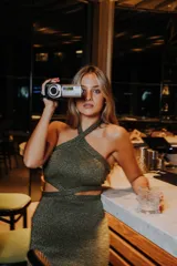 Vestido corto de punto con lurex color violeta, con cuello halter cruzado y aberturas en la cintura.