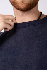 Remeron de algodón rústico con efecto de lavado gastado, corte oversize, cuello redondo y mangas cortas con terminaciones al corte.