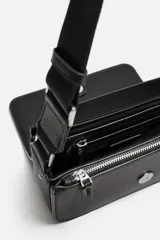 Bandolera negra con acabado grabado, compartimento principal con cierre de solapa imantada, bolsillo interno con cierre y bolsillo frontal con cierre. Incluye asa de hombro ajustable y monedero.