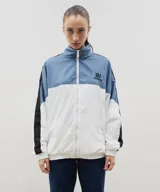 Campera de estilo deportivo confeccionada en tela tipo avión, con diseño tricolor en bloques de azul, blanco y negro. Presenta cuello alto, cierre frontal completo, puños y ruedo elásticos, y el logo de la marca bordado en el pecho.