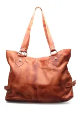 Cartera tipo shopper de cuero en color marrón, con diseño de doble asa para hombro y detalles de argollas metálicas en las uniones. Presenta costuras verticales visibles en el frente y correas laterales con hebillas ajustables.