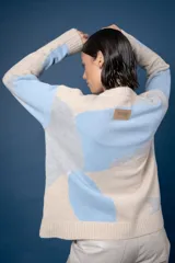 Buzo de punto con diseño abstracto que simula un paisaje, cuello redondo y mangas largas. Confeccionado en lana, presenta una combinación de colores en tonos beige, celeste y gris.