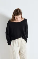 Sweater de punto de corte amplio y holgado, con cuello barco y mangas largas. Presenta una textura esponjosa y un diseño minimalista.