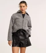 Short corto color marrón oscuro, confeccionado en poliuretano (PU) con textura que imita el cuero. Presenta cintura elástica en la parte trasera, lazo delantero para ajustar y recortes decorativos.