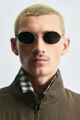 Cazadora de hombre color verde oliva, estilo bomber o Harrington, con cuello subido, cierre frontal de cremallera y puños y bajo elásticos. Presenta bolsillos de plastrón con solapa en el pecho y bolsillos de vivo en la cadera.