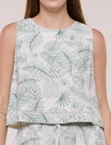Blusa crop sin mangas de color blanco con estampado botánico de hojas verdes, cuello redondo y detalle de puntilla calada en el ruedo.