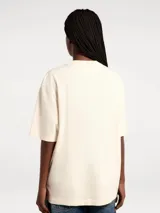 Camiseta color crema de corte amplio con estampado de paisaje costero enmarcado por columnas y la frase "Blue Horizon" en celeste.