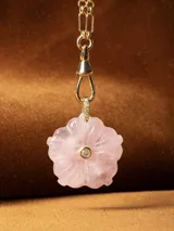 Collar con cadena de eslabones tipo bolita dorada y dije de piedra natural tallada en forma de flor con una pequeña circonia incrustada en el centro.