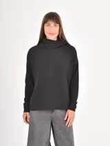 Polera de manga larga en color negro, confeccionada en tejido de punto con textura acanalada fina. Presenta un cuello alto tipo polera, corte holgado y puños ajustados.