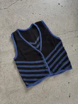 Chaleco calado negro con diseño de rayas diagonales rojas, beige y blancas.