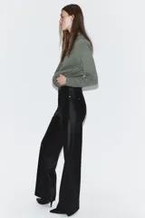 Pantalón de tiro medio confeccionado en tejido efecto piel, con diseño de cinco bolsillos y cierre frontal con cremallera y botón.