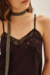 Top de crepe viscosa color verde azulado, con escote en V adornado con encaje y bordados florales con lentejuelas. Posee breteles finos regulables y elástico en la espalda.