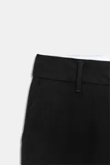 Pantalón negro de tiro bajo, corte recto con trabillas en la cintura y raya planchada al frente. Cuenta con bolsillos laterales y falsos bolsillos de vivo en la espalda. Cierre frontal con cremallera, botón interior y ganchos metálicos.