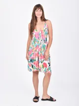 Vestido corto con estampado floral multicolor sobre fondo blanco, de escote en V y tirantes finos. Presenta un diseño entallado en el busto y falda con ligero vuelo.