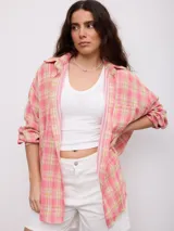 Camisa oversize de manga larga con estampado a cuadros en tonos rosado, amarillo y blanco, cuello camisero y cierre frontal con botones.