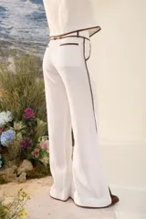 Pantalón azul marino de corte wide leg con detalles en tono marrón tostado en la cintura, bolsillos y bordes laterales, cuenta con trabillas para cinturón y cierre frontal.