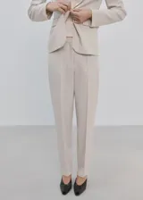 Pantalón de vestir de tiro medio, color beige, con diseño de pernera recta, trabillas para cinturón y bolsillos laterales.