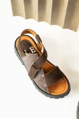 Sandalias de plataforma con suela track, confeccionadas en una combinación de cuero liso y cuero con textura croco. Presentan tiras anchas en el empeine y cierre con hebilla ajustable en el talón.
