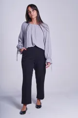 Blusa de manga larga color rosado, con cuello redondo y puños elásticos con volados y lazos decorativos. Presenta un diseño holgado con frunces en el escote.