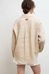 Camisa oversize de lino, color tostado, con cuello clásico, cierre frontal de botones y bolsillo en el pecho.