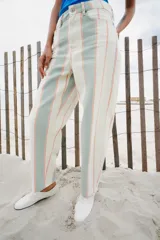 Pantalón jeans de corte tapered y tiro medio, con diseño de rayas verticales en tonos blanco, verde menta y naranja.