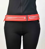 Riñonera deportiva color naranja con dos compartimentos con cierre y banda reflectiva.