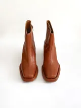 Bota de caña media color óxido, confeccionada en cuero, con plataforma y taco cuadrado texturizado, punta cuadrada y cierre lateral.