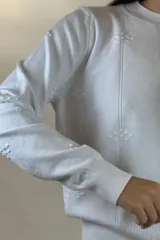 Buzo de hilo color verde menta, de cuello redondo y manga larga, con diseño de líneas verticales en relieve y pequeños detalles bordados.