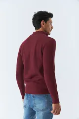 Sweater de tejido de punto acanalado en color negro, con cuello alto y cierre frontal parcial. Cuenta con mangas largas y un pequeño logo bordado en el ruedo.