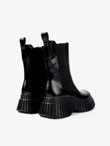 Botín Chelsea negro de cuero con elásticos laterales y tirador trasero. Plataforma con suela dentada de goma.