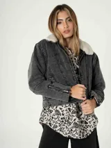 Campera de jean azul con cuello de piel sintética color crema, cierre frontal y cierres decorativos en los puños.