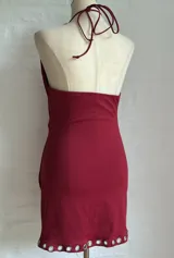 Minivestido rojo con escote halter pronunciado y detalle de ojalillos metálicos en el escote y el ruedo.